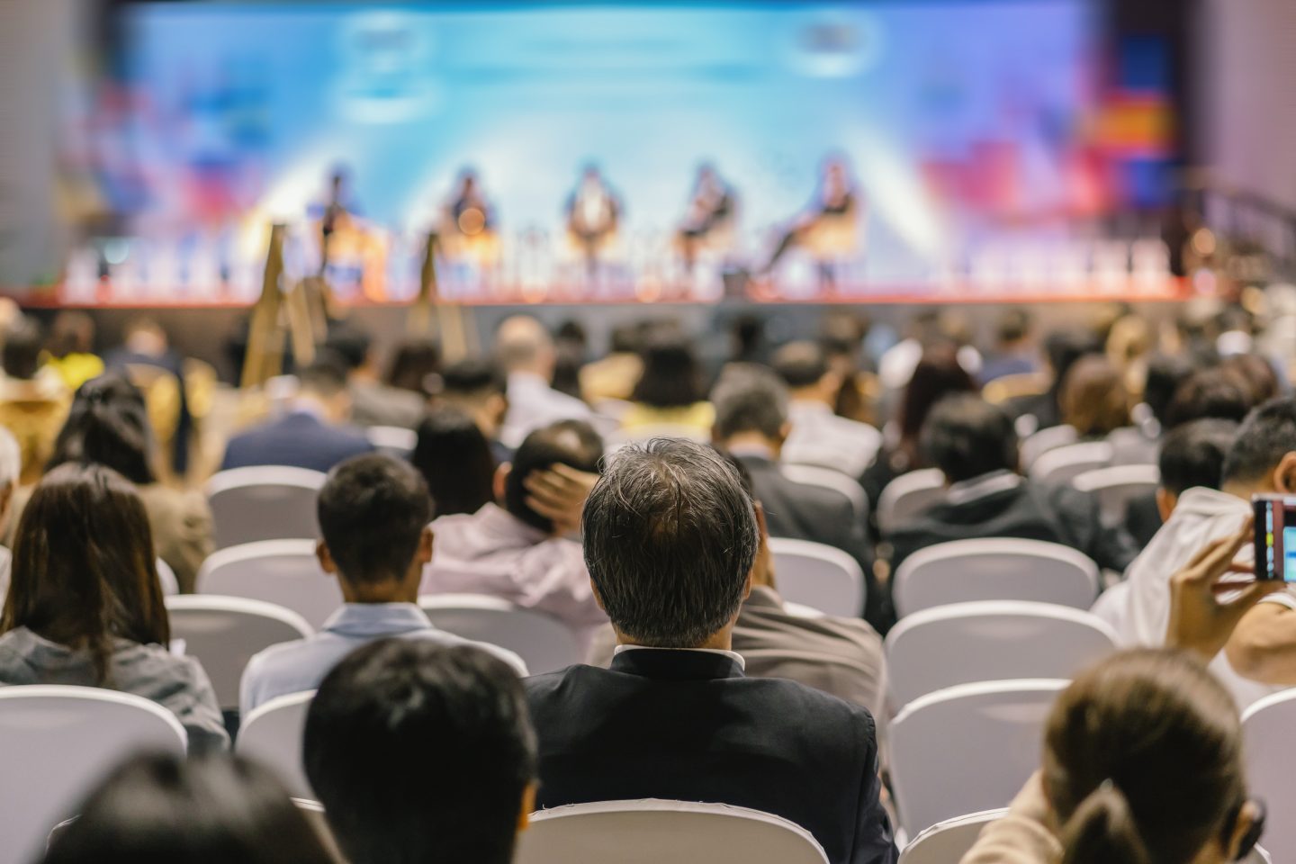rear-view-of-audience-listening-speakers-on-the-stage-in-the-conference-hall-or-seminar-meeting-1-e1700247927731.jpg